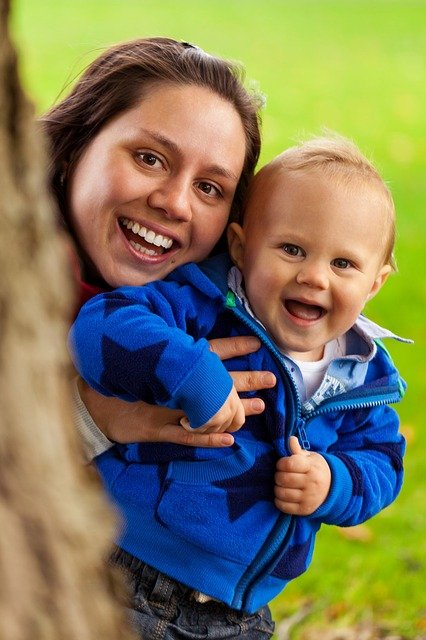 Frau und Kind neben Baum lachen in Kamera