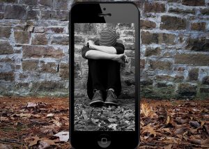 Cybermobbing Junge vor Mauer eingerahmt von Smartphone