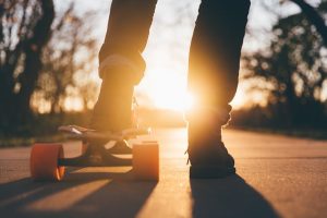 Jugendlicher auf Skateboard vor Sonnenuntergang