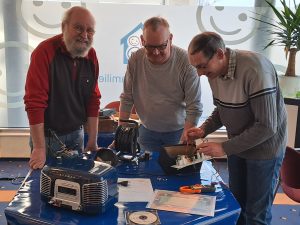 Drei Männer reparieren Elektro-Geräte im Reparatur-Café