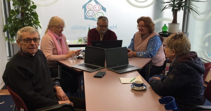 Besucherinnen und Besucher von Miteinander digital sitzen an einem Tisch vor sich Computer