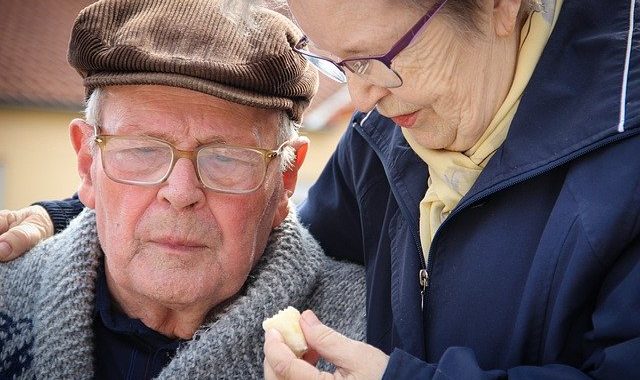 Ältere Frau kümmert sich um älteren Mann