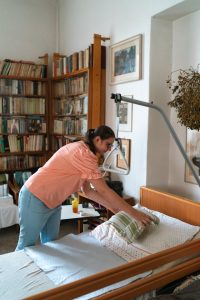 Frau legt Kissen auf Pflegebett