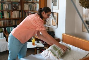 Frau legt Kissen auf Pflegebett