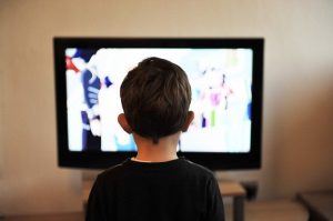 Junge sitzt vor Fernseher und schaut hinein