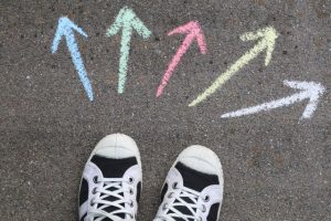 Schuhe auf Asphalt davor bunte Pfeile