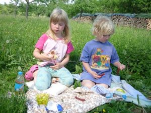 Zwei Mädchen sitzen auf Wiese und picknicken
