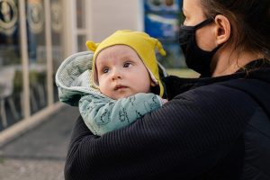 Mutter mit Maske hält ihr Baby im Arm