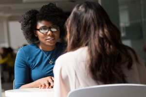 Zwei Frauen im Gespräch an einem Tisch sitzend